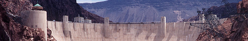A large water damn, with a background of mountains.